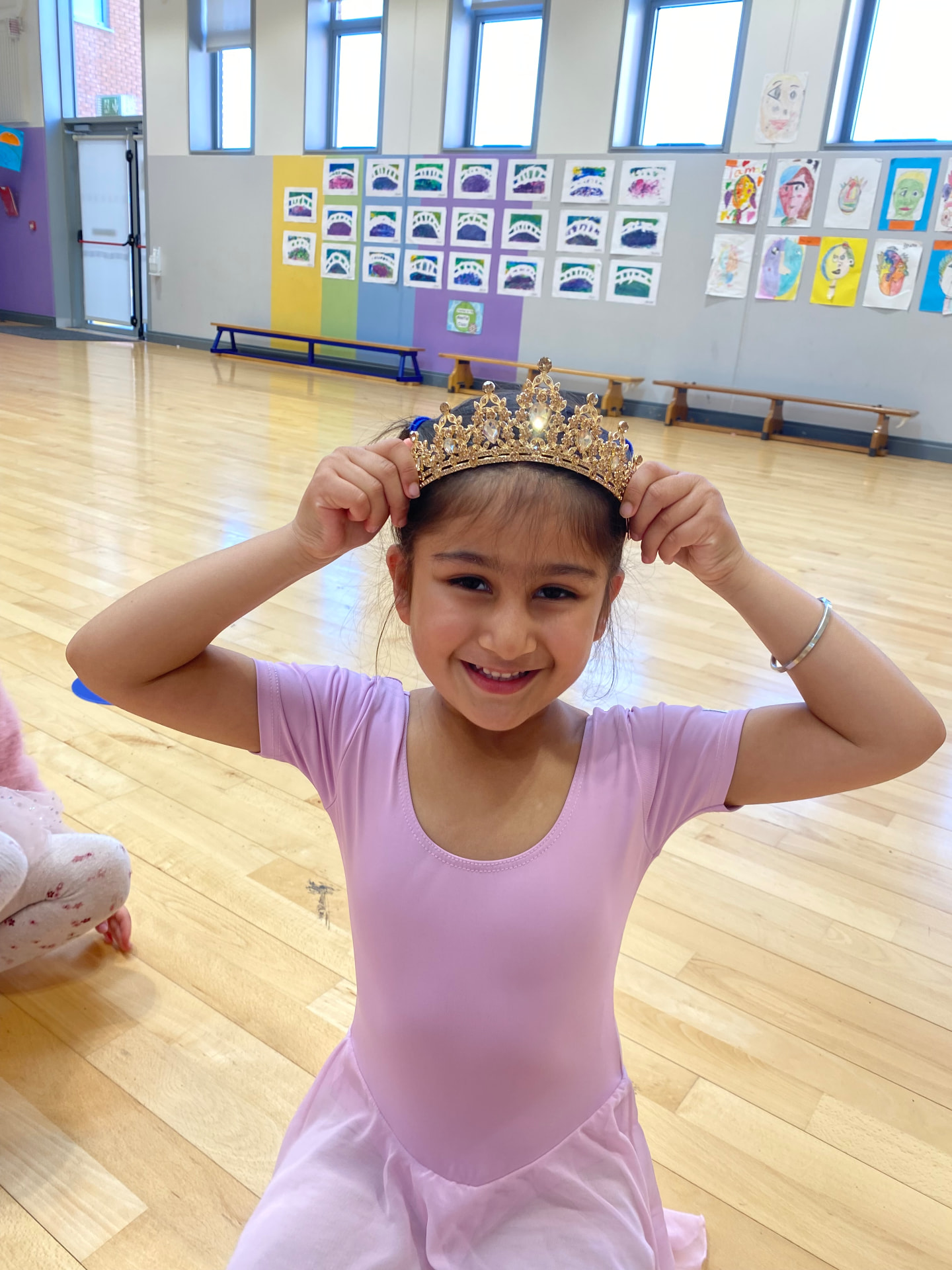 Young dancer trying on a sparkling tiara in class